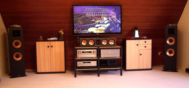 Ein schon Kultstatus und klassische Eleganz beinhaltendes Set-up at Ronny´s . Sherwood´s Combination fantastique A965/P965 treibt ein Paar Klipsch Reference RF7 in Verbindung mit Ground-Effect schaffendem Klipsch RSW12 Active-Subwoofer ( versteckte Placierung ) . Entsprechende Center und Rears aus der Reference-Serie ( RC 64 + 2 x RS 62 ) füllen den Raum . Plasma 50 Zoll ist Standart bei unseren Installationen . Ebenso nutzen wir gerne die Flexibilität der Lovan AV-Racks , hier : Lovan Pyramid AV black-gold . Verkabelungen komplett mit musikalischem Viablue Stoff . Davon kann man nie genug haben . Hier ist die Zufriedenheit erstmal für sehr lange Zeit eingezogen - wobei , auch das ist steigerungsfähig .....